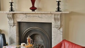 Una chimenea con una mesa de vidrio al frente, un sofá rojo y una revista sobre la mesa.