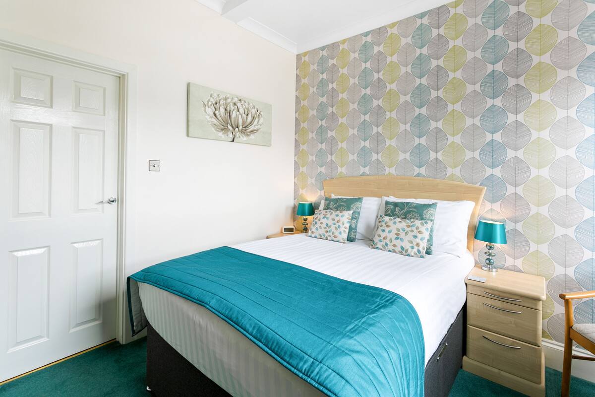 A neatly arranged bedroom with a bed, bedside tables, a nightstand, and a chair.