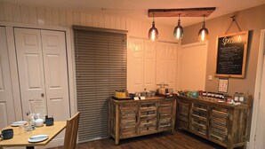A cozy kitchen with wooden cabinets, a wooden dining table, and a chalkboard menu on the wall. - Ashburton House (Scarborough)