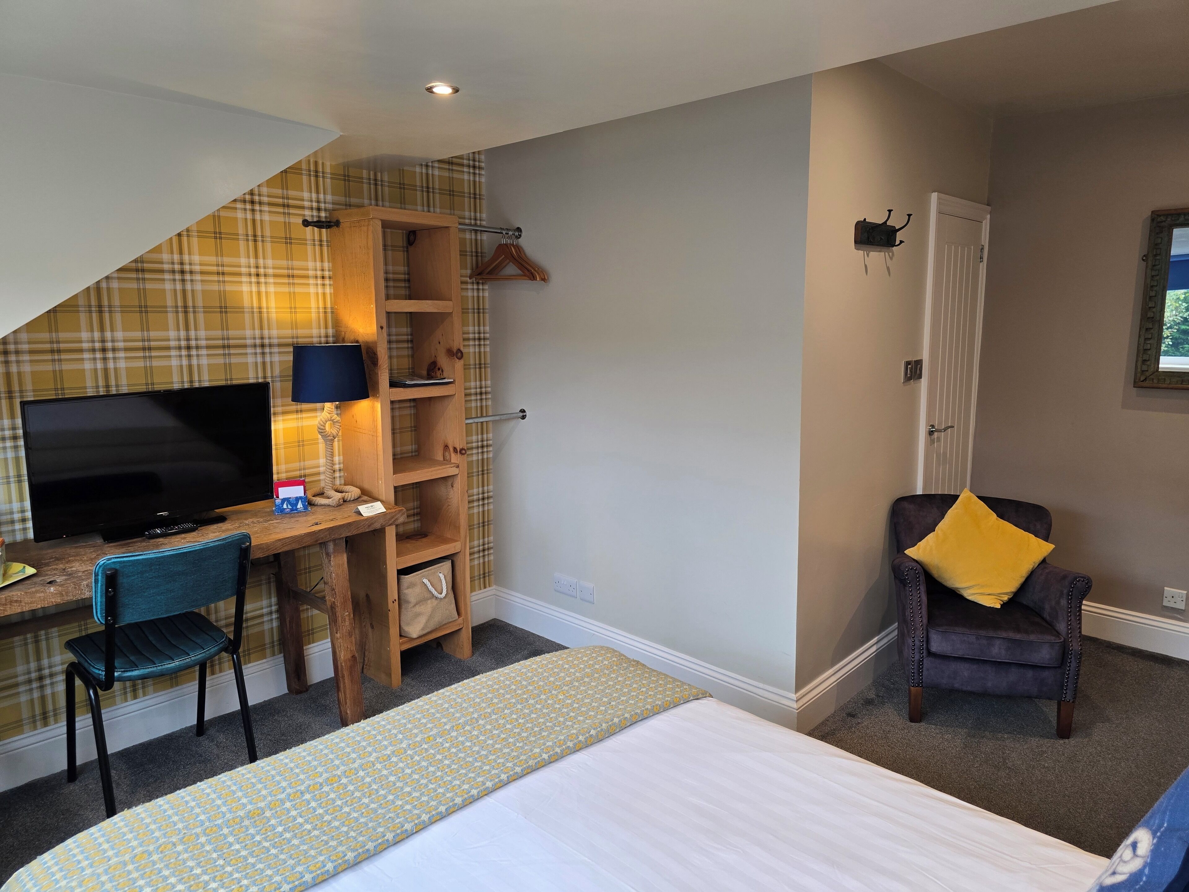 Ein Schlafzimmer mit Bett, Schreibtisch mit Fernseher, Stuhl und Kleiderschrank.