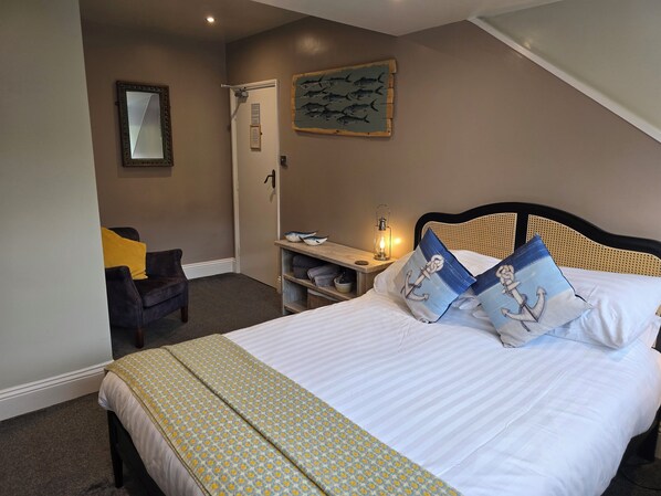A bedroom with a bed, a nightstand, a chair, a door, and a wall with a fish mural. - Ashburton House (Scarborough)