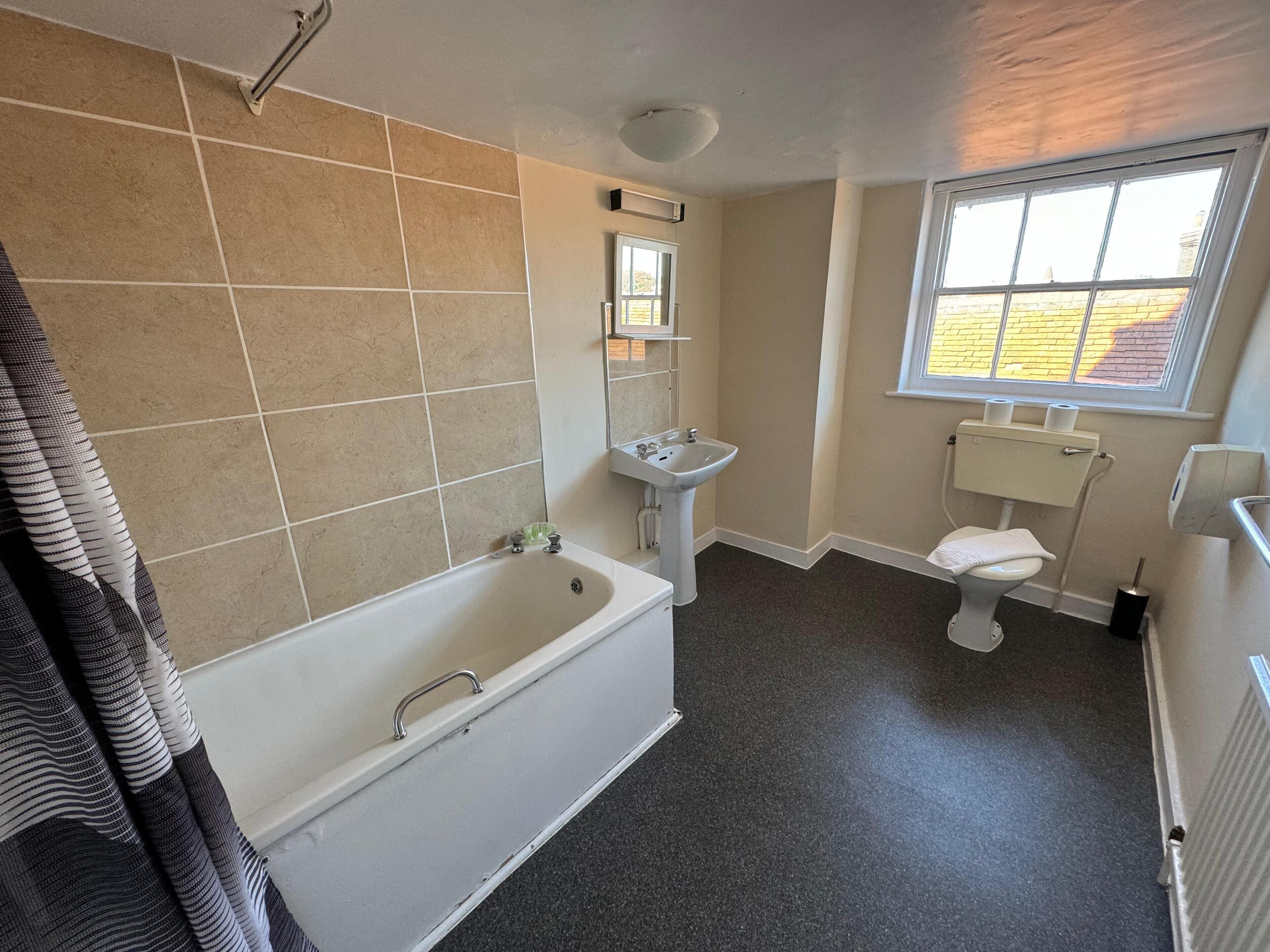 A bathroom with a bathtub, sink, toilet, and a window.