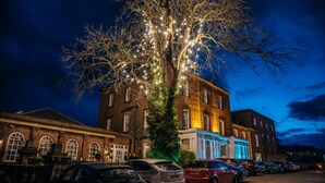 A tree decorated with lights, a parking lot, and buildings with illuminated windows. - Hotel Bannatyne Darlington (Darlington)