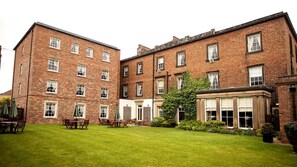 A traditional brick building with multiple windows and a well-maintained lawn.