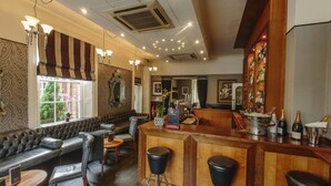A bar area with a wooden counter, bar stools, and a seating area with a sofa and chairs. - Hotel Bannatyne Darlington (Darlington)