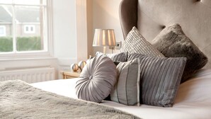 A neatly made bed with a tufted headboard, multiple pillows, and a fluffy blanket. - Hotel Bannatyne Darlington (Darlington)