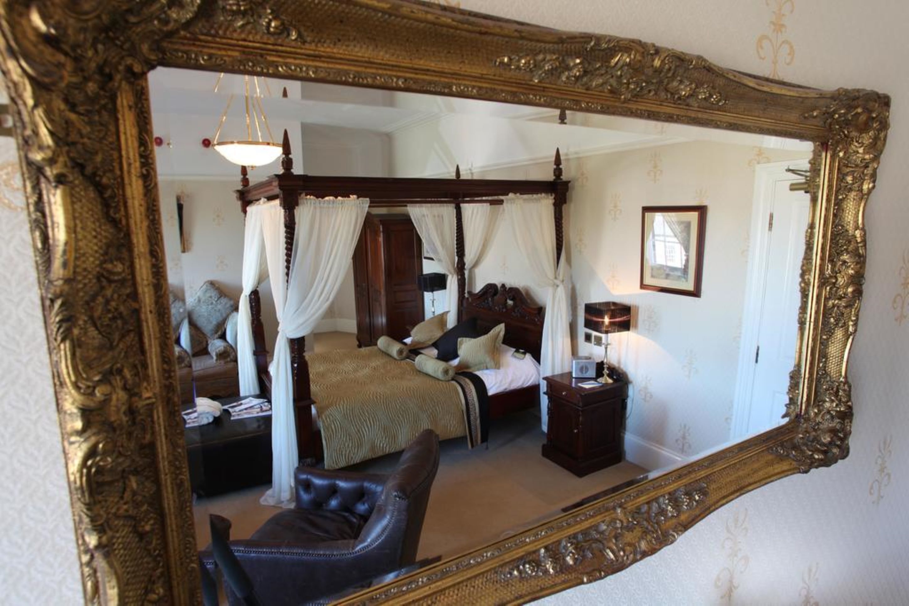 A bedroom with a four-poster bed, a nightstand, and a chair.