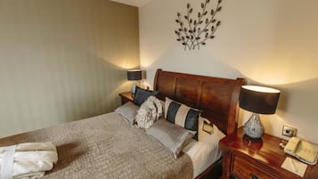 A neatly made bed with a wooden headboard, a bedside lamp, and a wall-mounted decorative piece.