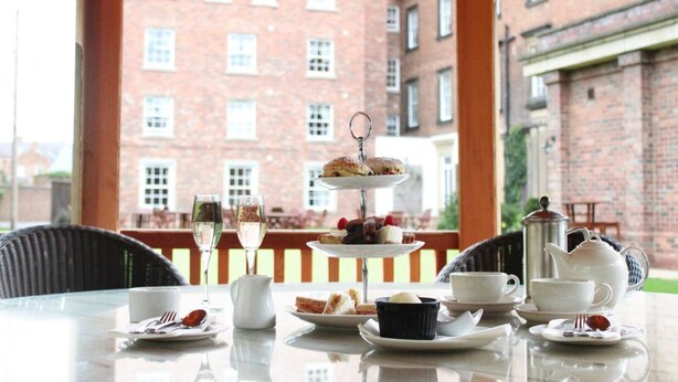 A table set for tea service with a tiered dessert stand, a teapot, cups, and a pitcher. - Hotel Bannatyne Darlington (Darlington)