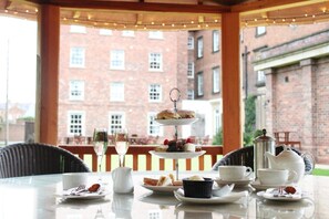 A table set for tea service with a tiered dessert stand, a teapot, cups, and a pitcher.