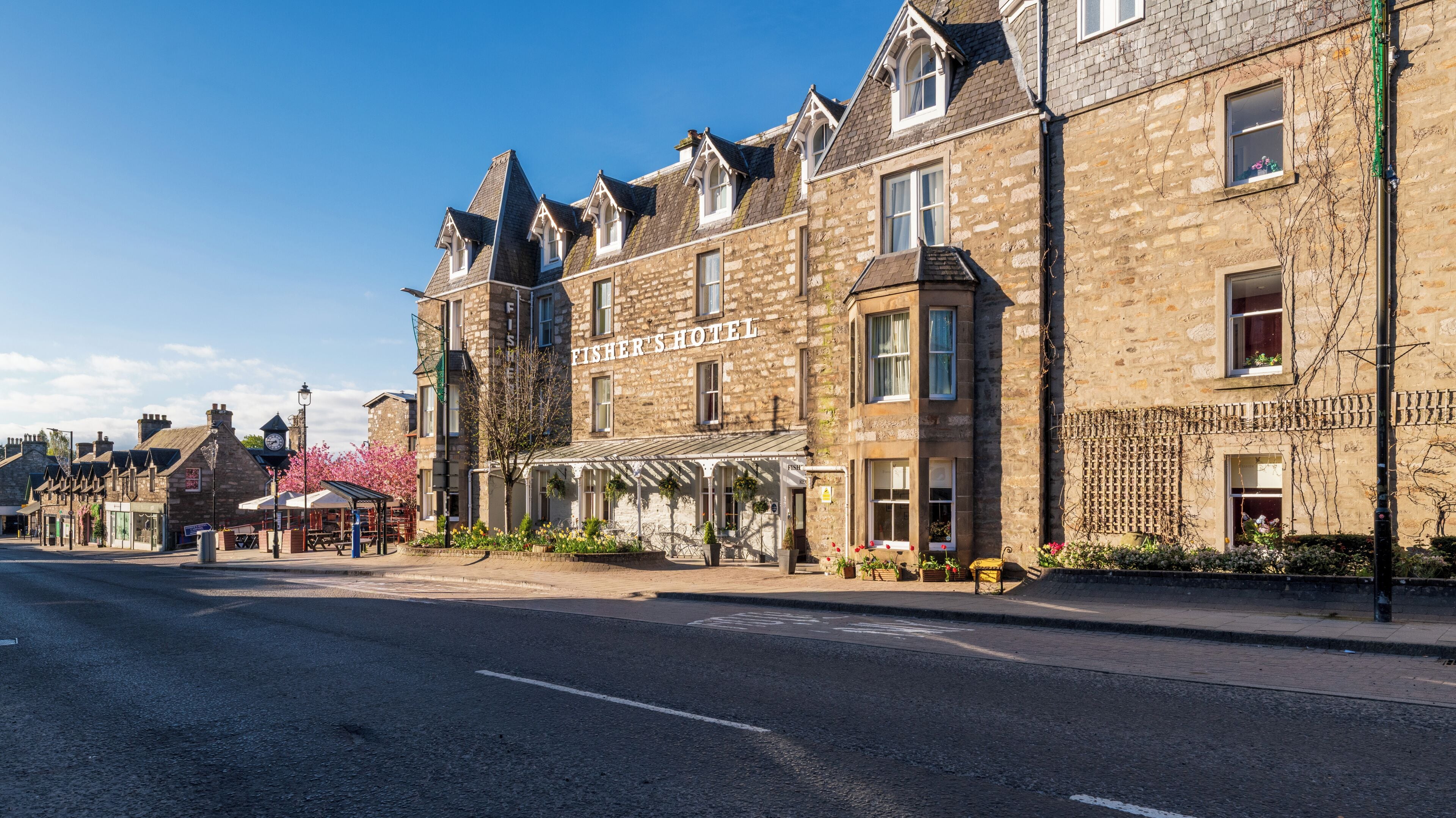 A stone building with a sign reading 'Fisher's Hotel' and a covered outdoor seating area.