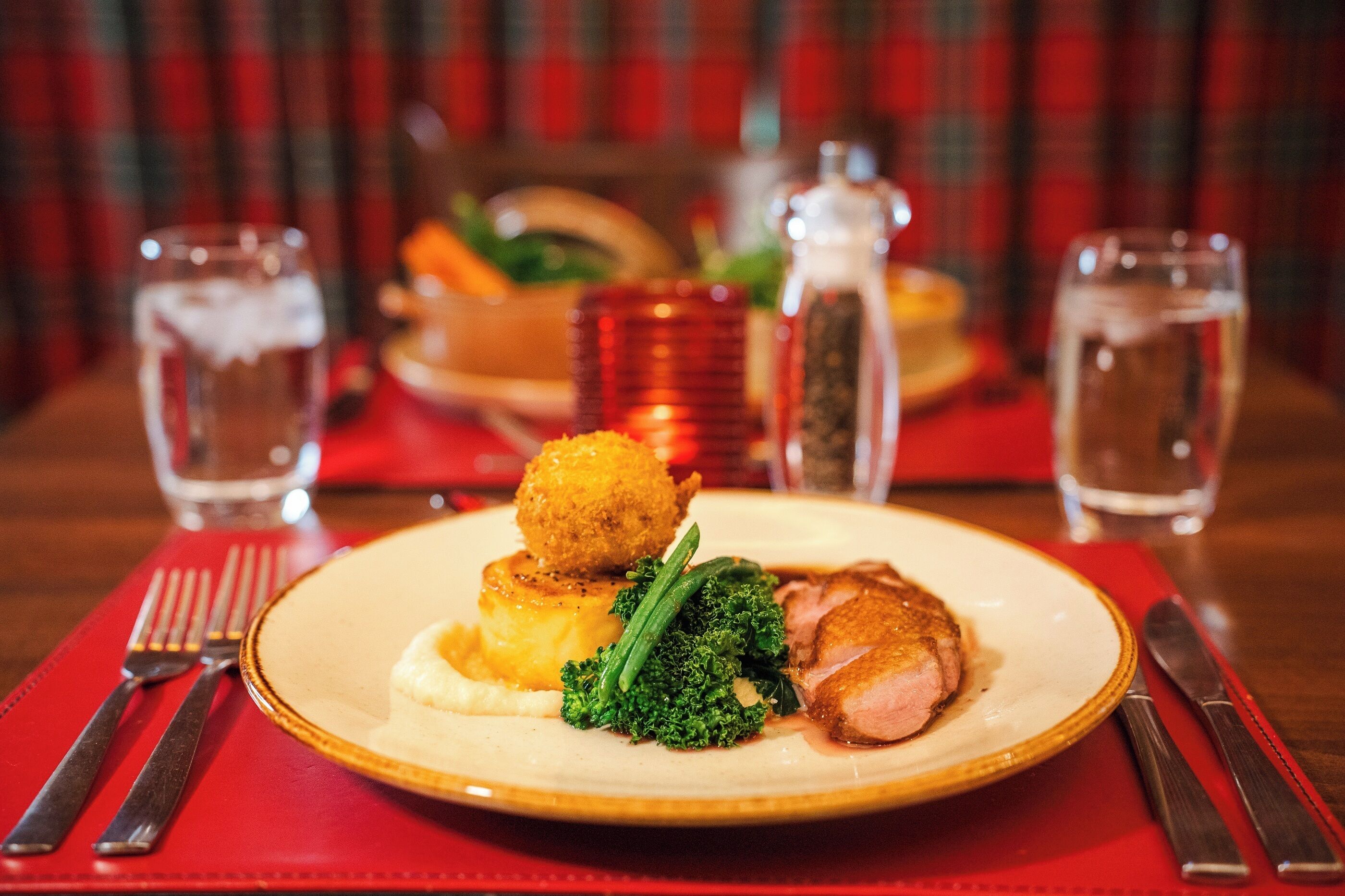 A plate of food with a variety of items including a piece of meat, broccoli, and mashed potatoes.