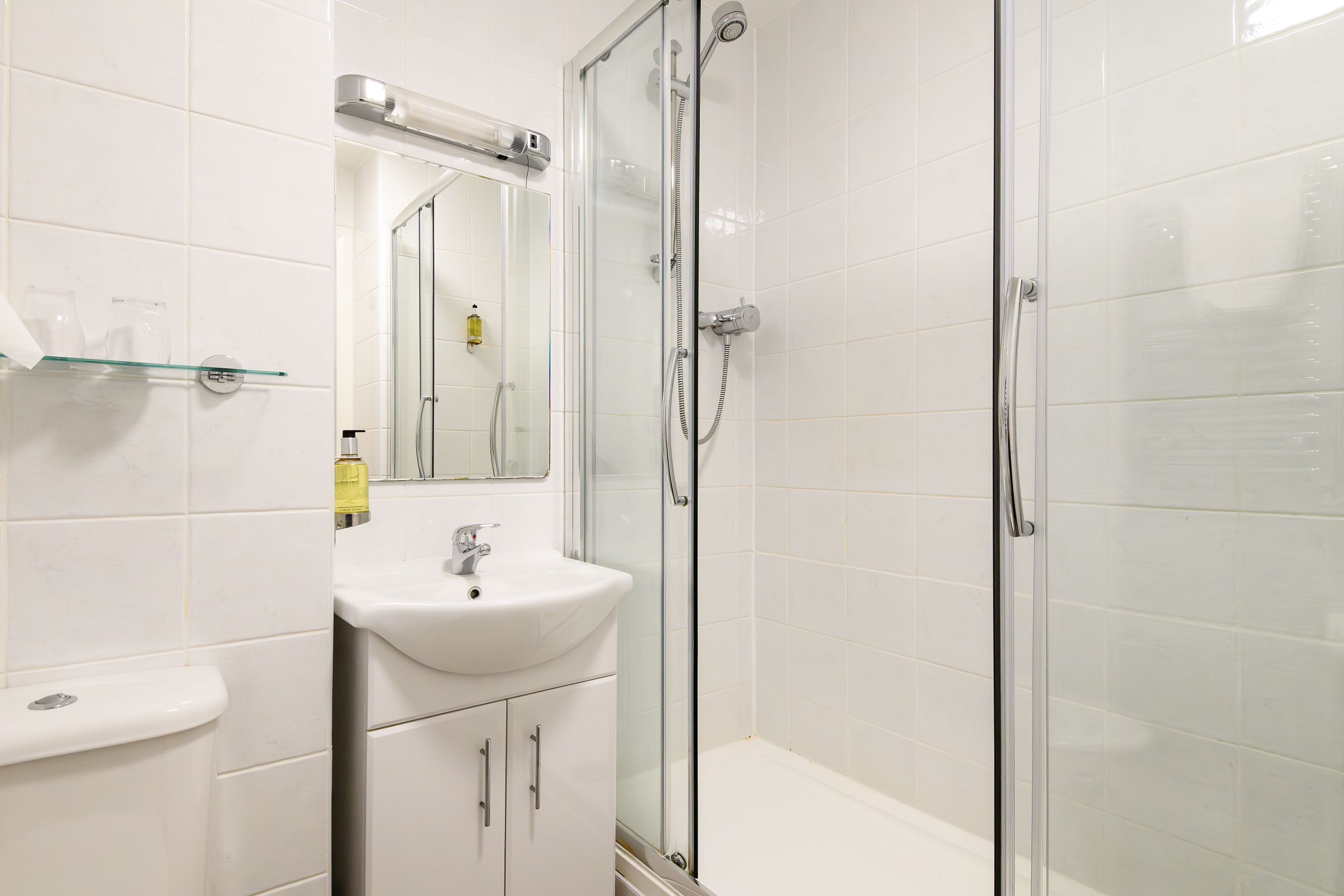 A modern bathroom with a glass-enclosed shower, a white sink, and a mirror above it.