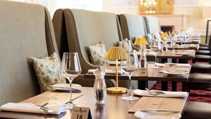 A dining area with tables set for two, each with a number, wine glasses, cutlery, and a lamp. - Fisher's Hotel (Pitlochry)
