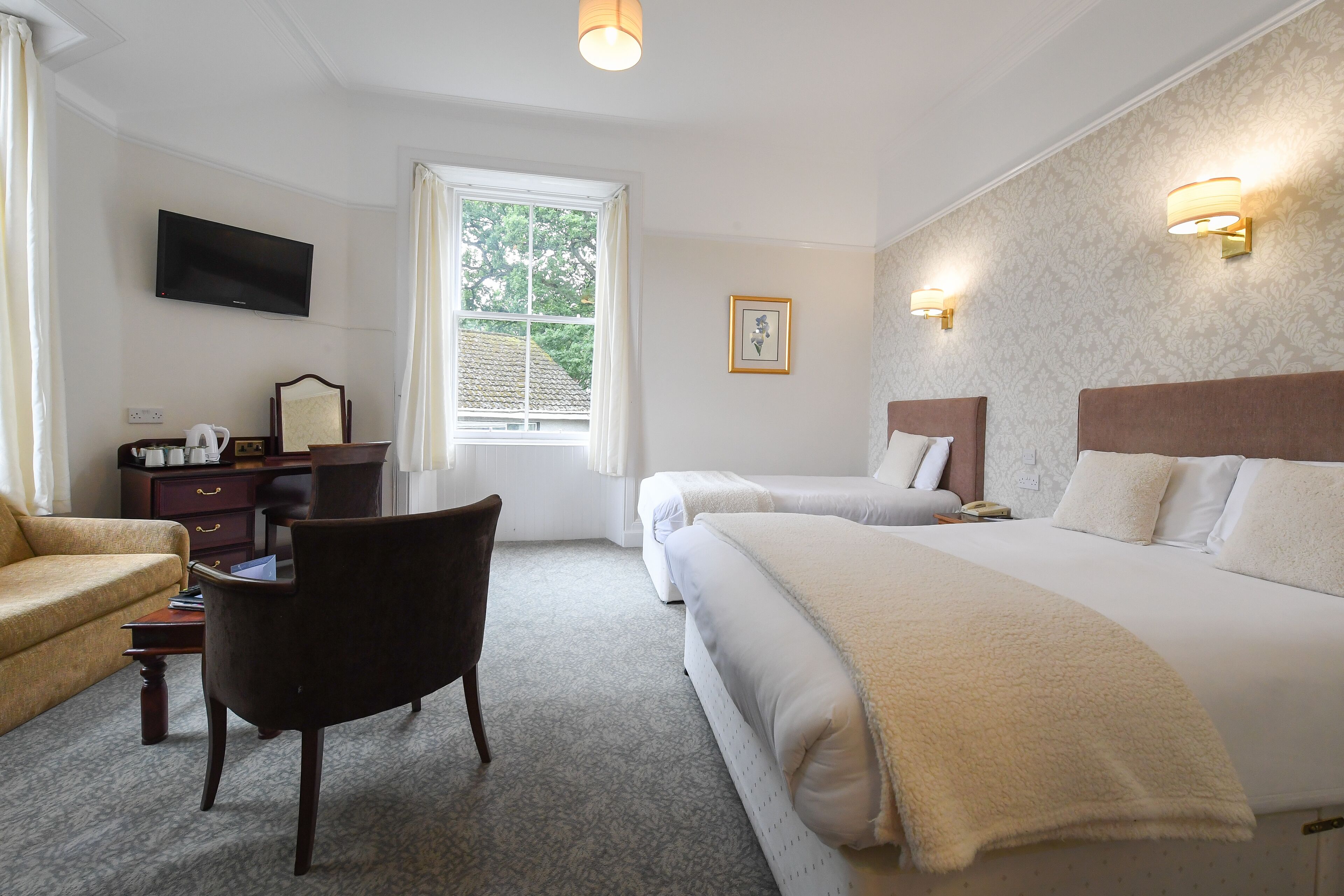 A hotel room with a large bed, a desk with a chair, a television, and a window with curtains.