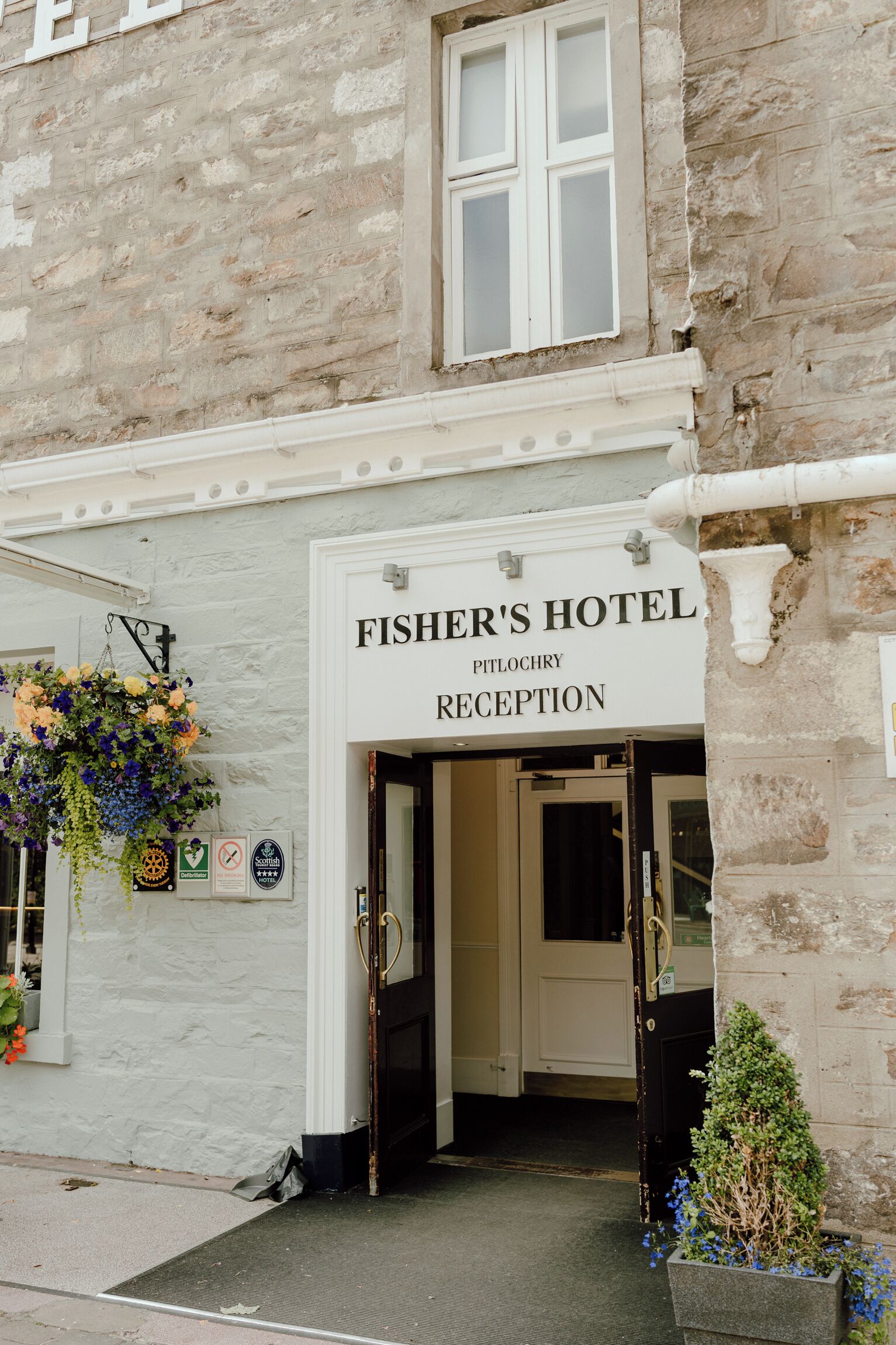 Un edificio in pietra con un cartello che indica 'FISHER'S HOTEL PITLOCHRY RECEPTION'.