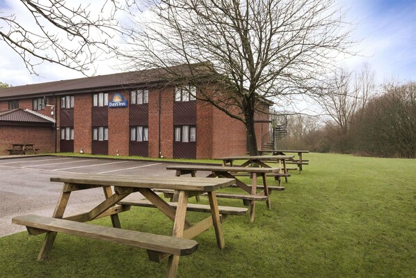 A Days Inn with a brick building, picnic tables, and a parking lot.