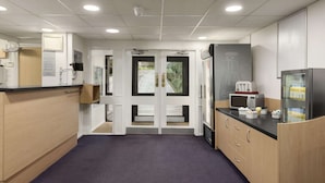 A modern kitchen with wooden cabinets, a black countertop, and a microwave.