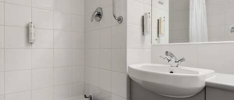 A modern bathroom with a bathtub, two sinks, a shower, and a mirror.