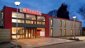Un edificio moderno con una facciata rossa e un'insegna che riporta la scritta "RAMADA".