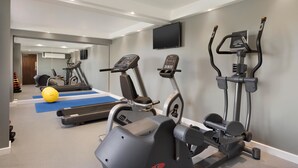 Una palestra con tapis roulant, macchine ellittiche e una cyclette.