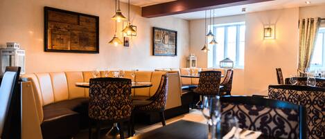 A restaurant with booths, round tables, and patterned chairs.