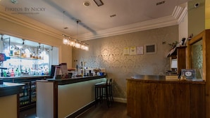 Zona de bar con mostrador, taburetes y una variedad de botellas.