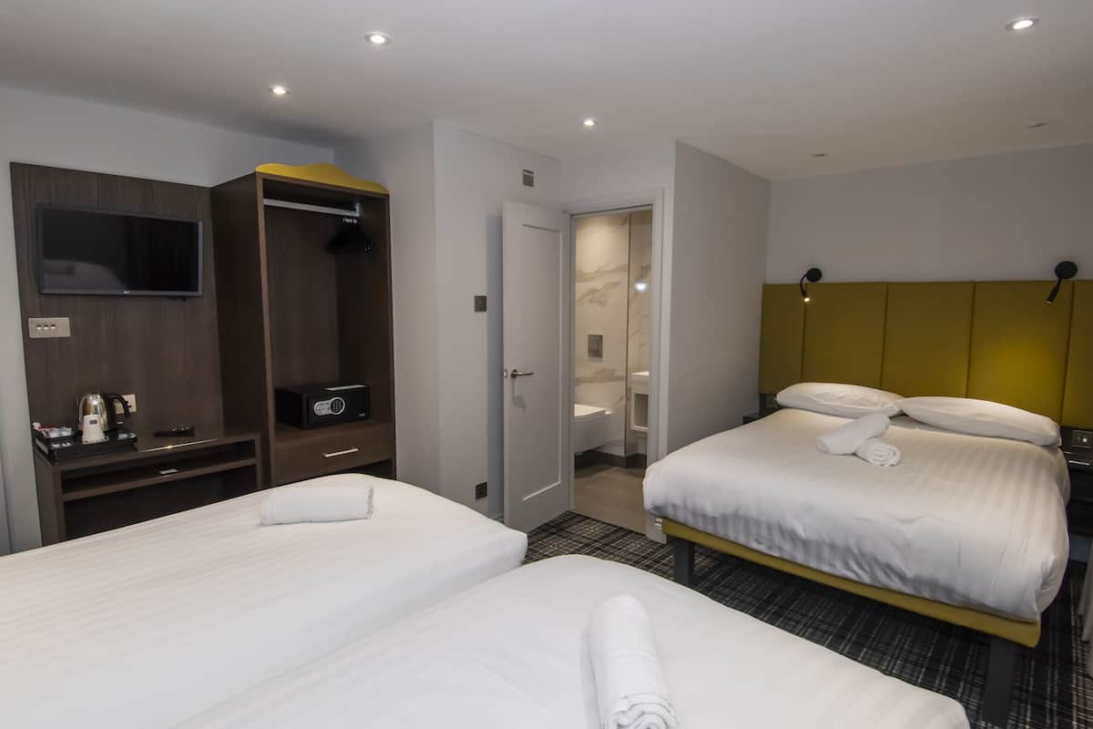 Quarto de hotel com duas camas, televisão, guarda-roupa e banheiro.