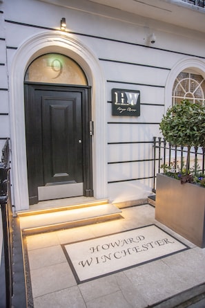A hotel entrance with a dark door, a sign reading "1W King Charles," and a doormat that says "Howard Winchester." - Howard Winchester Hotel (London)