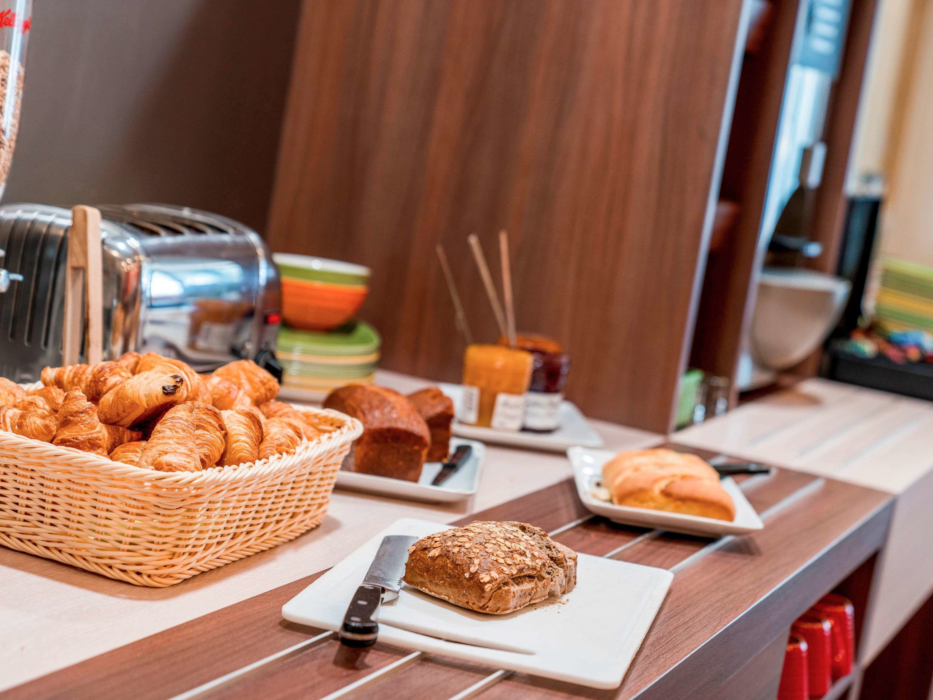 A breakfast buffet with croissants, bread, and jams.