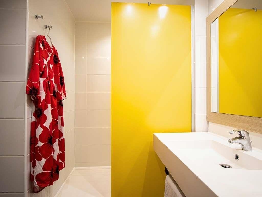 A bathroom with a white sink, yellow accent wall, and a red floral shower curtain.