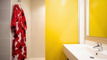 A bathroom with a white sink, yellow accent wall, and a red floral shower curtain.