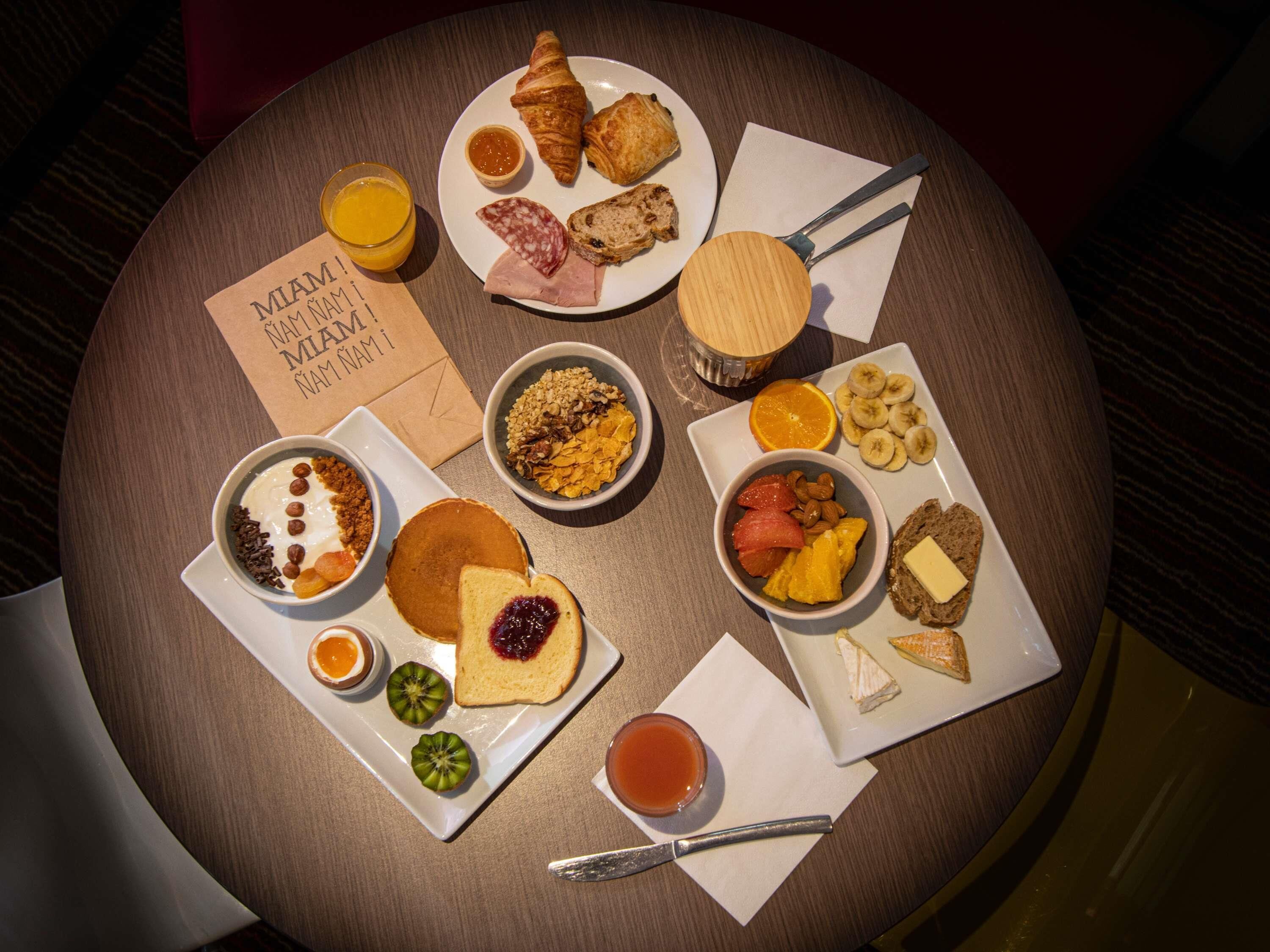 A breakfast spread on a round table with various food items and a napkin with a handwritten note.