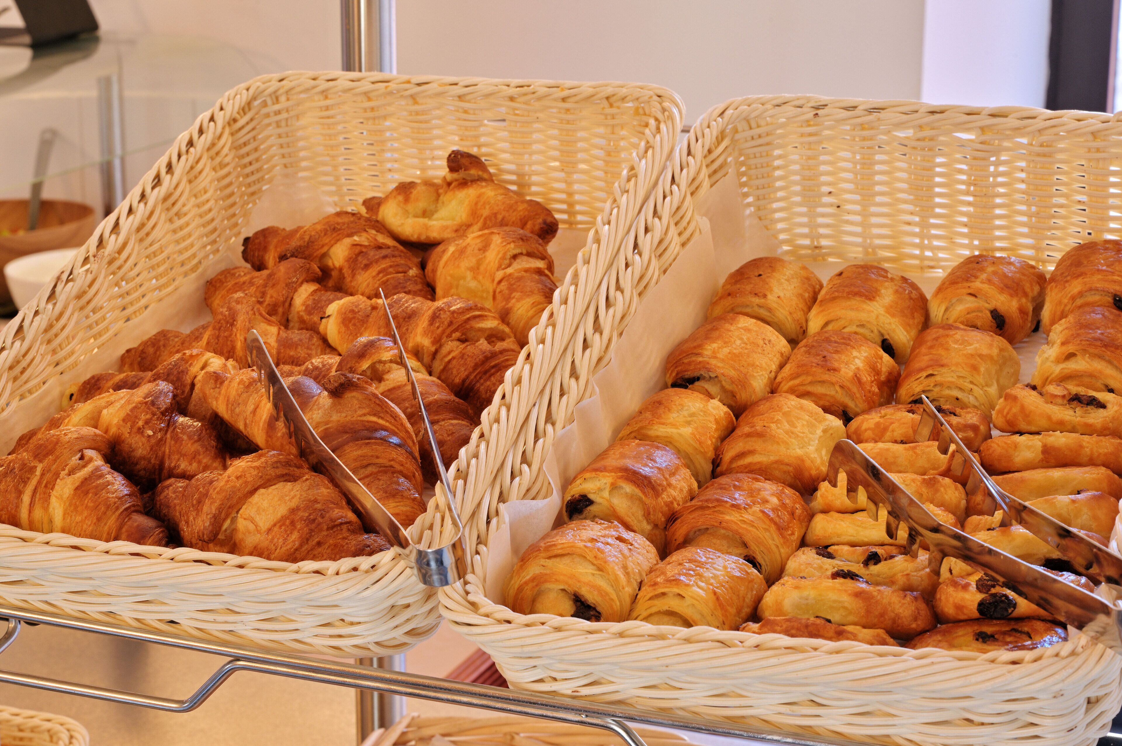 Twee rieten manden gevuld met croissants en chocoladebroodjes.