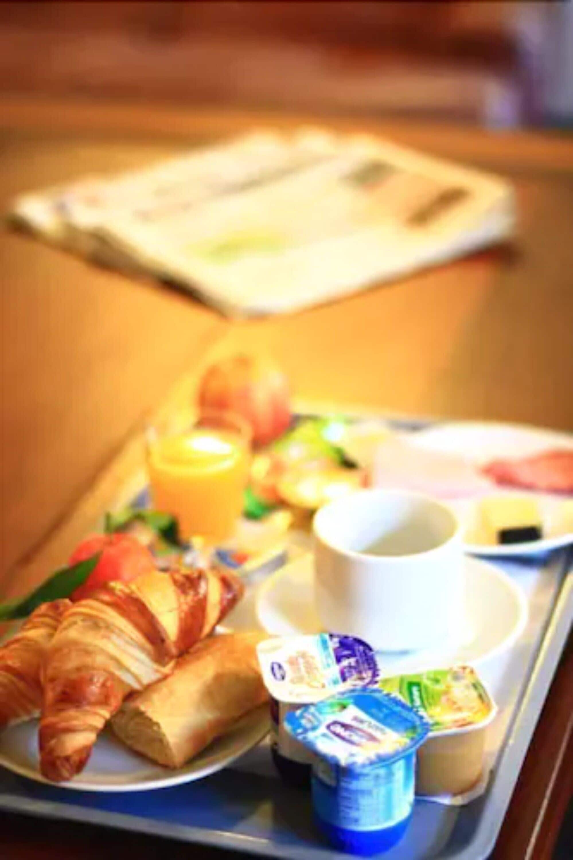 A tray with croissants, yogurt, a cup, and a plate with a meal.
