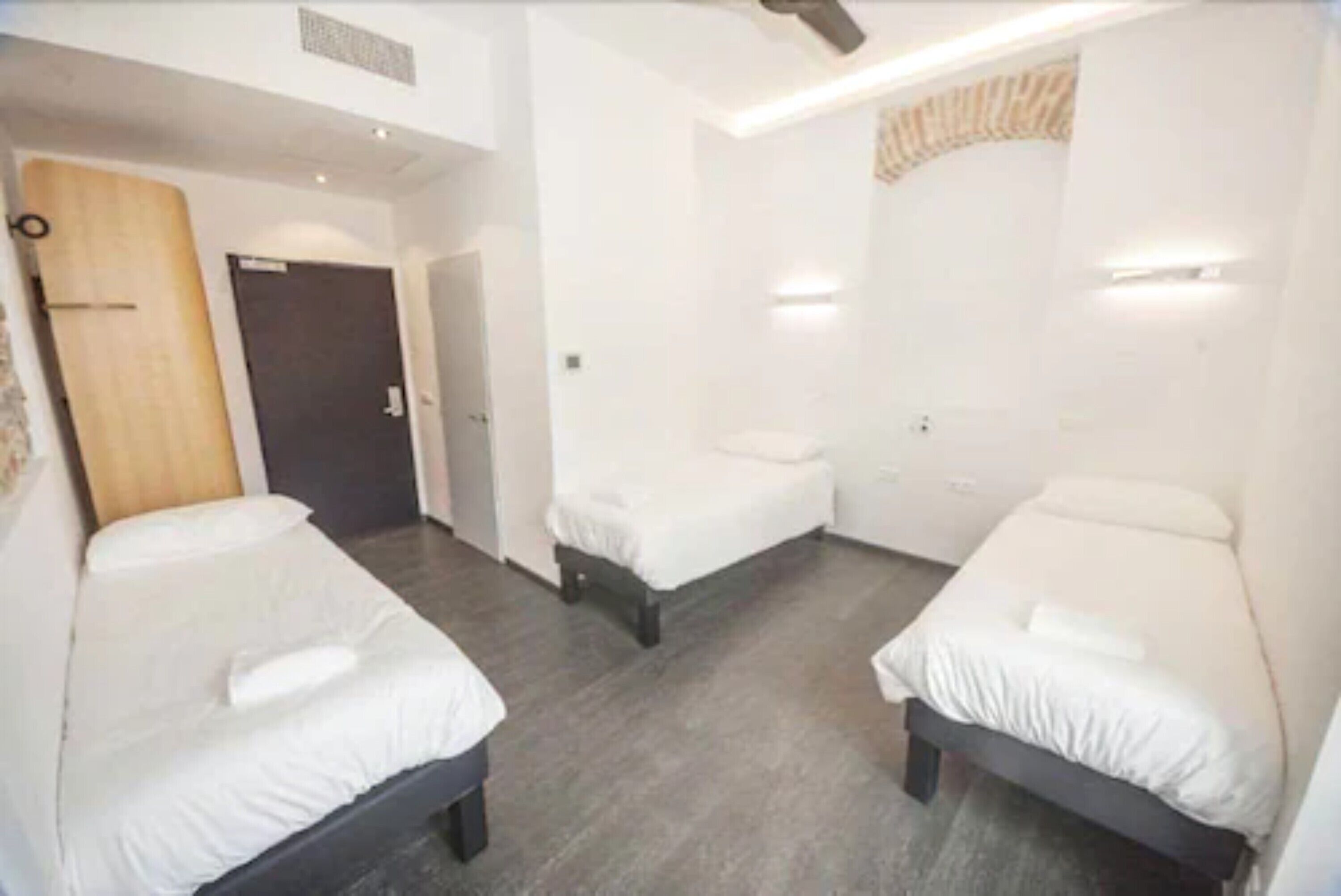 Een hotelkamer met twee eenpersoonsbedden, een houten deur en een kleine badkamer.