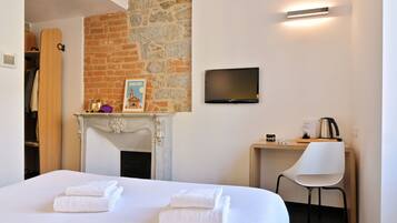 Quarto de hotel com cama, televisão, lareira e escrivaninha com cadeira.