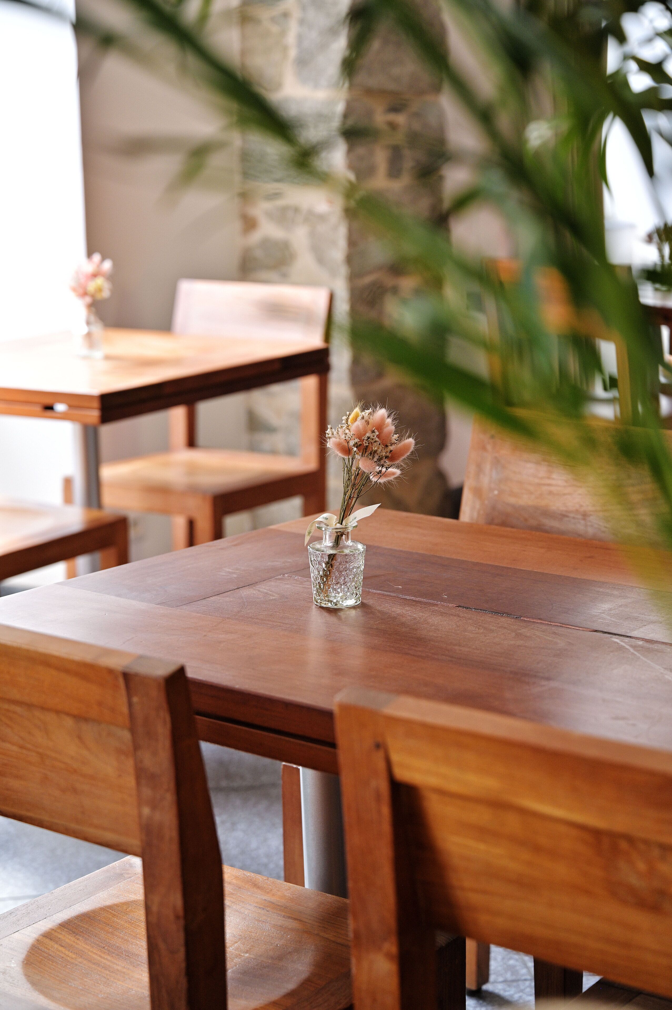 A wooden dining table with a clear glass vase containing dried flowers.