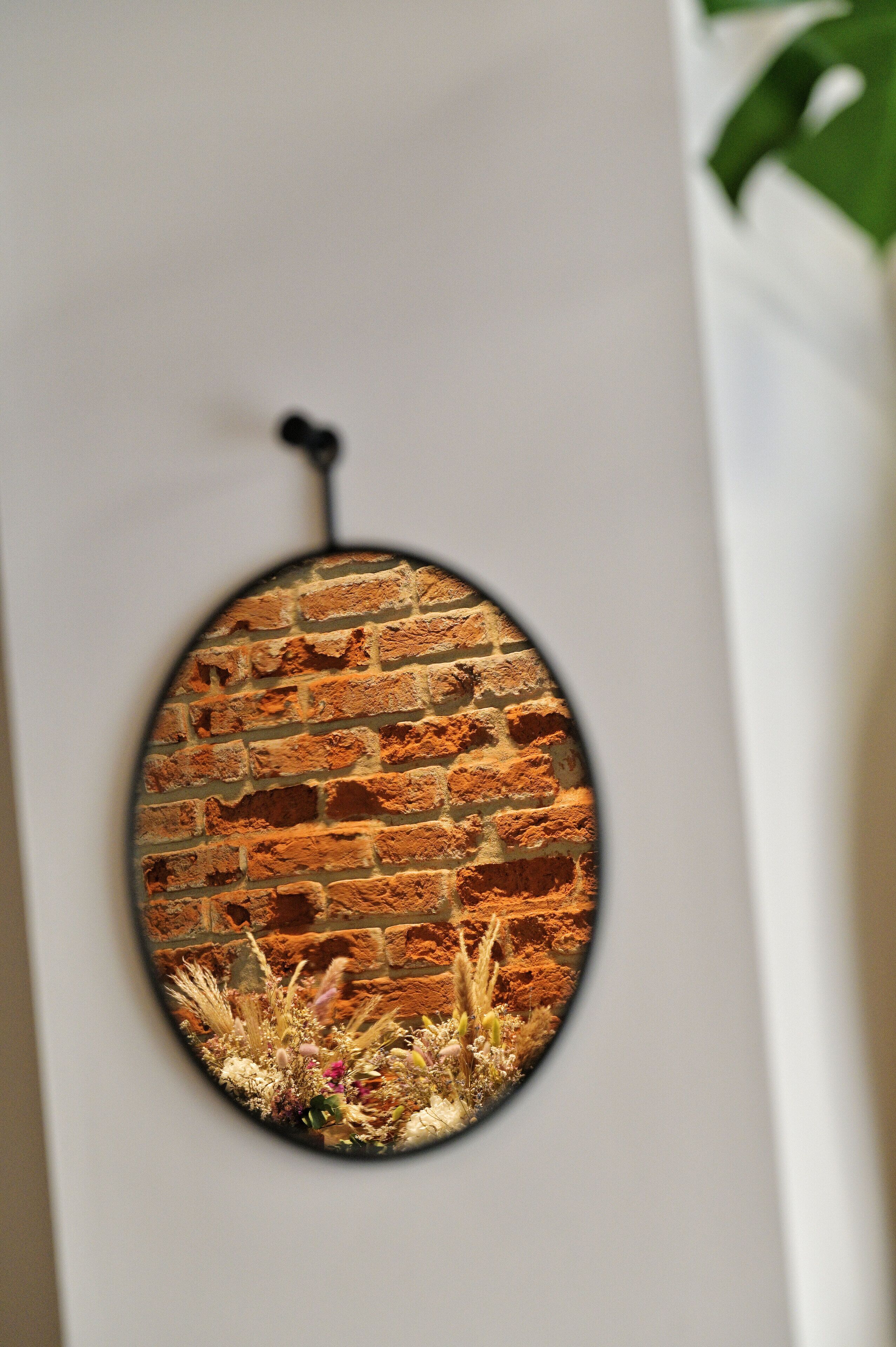 A circular artwork with a brick wall and plants.