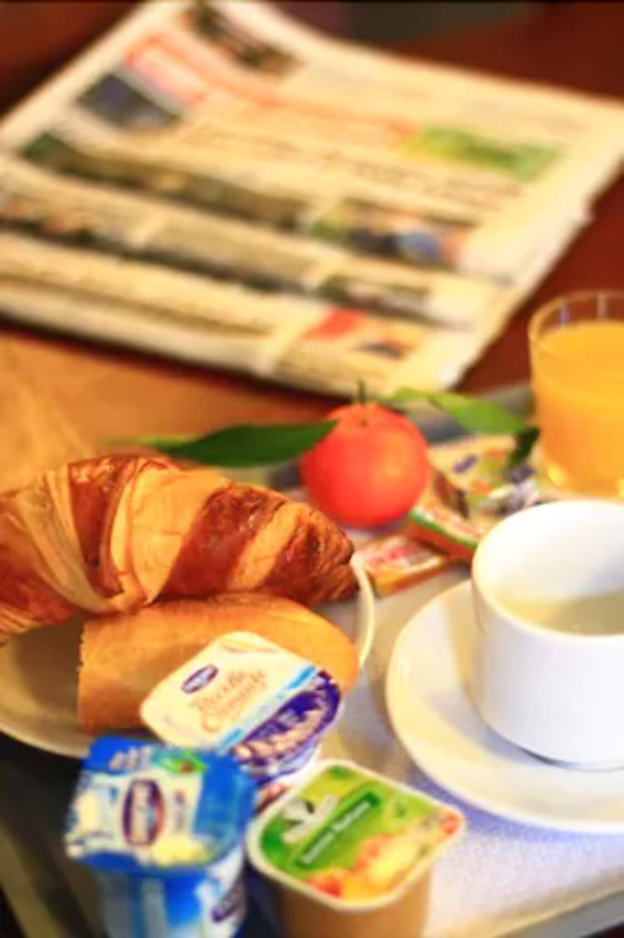 A breakfast tray with croissants, yogurt, a tomato, and a glass of orange juice.