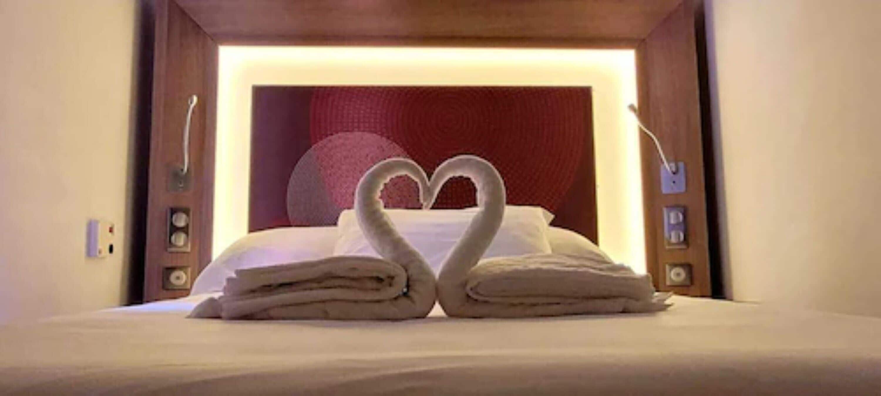 A bed with towels arranged in a heart shape.
