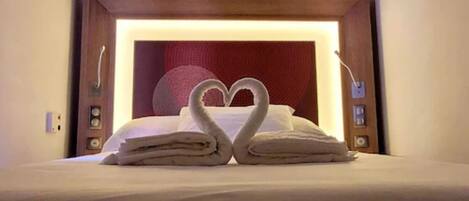 A bed with towels arranged in a heart shape.