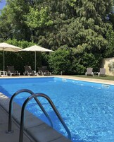 Una piscina al aire libre de temporada, sombrillas