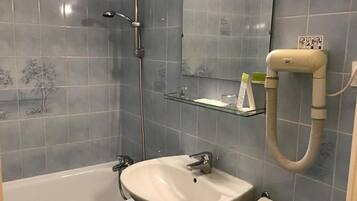 Een badkamer met een bad, wastafel en spiegel.