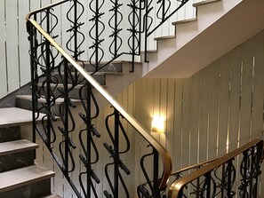 A staircase with black metal railings and a golden handrail. - Brit Hotel Europ Bergerac (Bergerac)