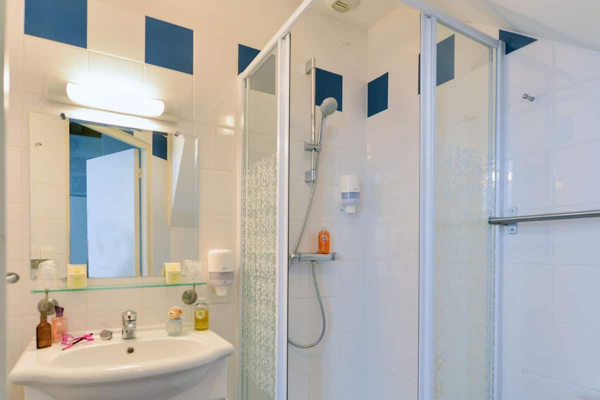 A bathroom with a glass-enclosed shower, a white sink with a mirror above it, and a toilet.