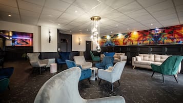 A modern lounge area with a variety of seating options, a large wall-mounted TV, and a colorful abstract mural.