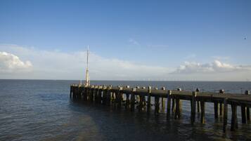 A pier extending into calm water with a clear sky above.