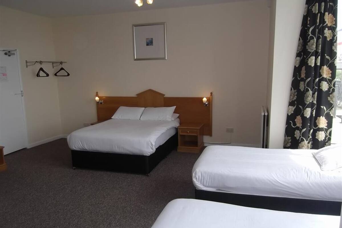 A hotel room with two single beds, a wooden headboard, a small bedside table, and a wall-mounted picture.
