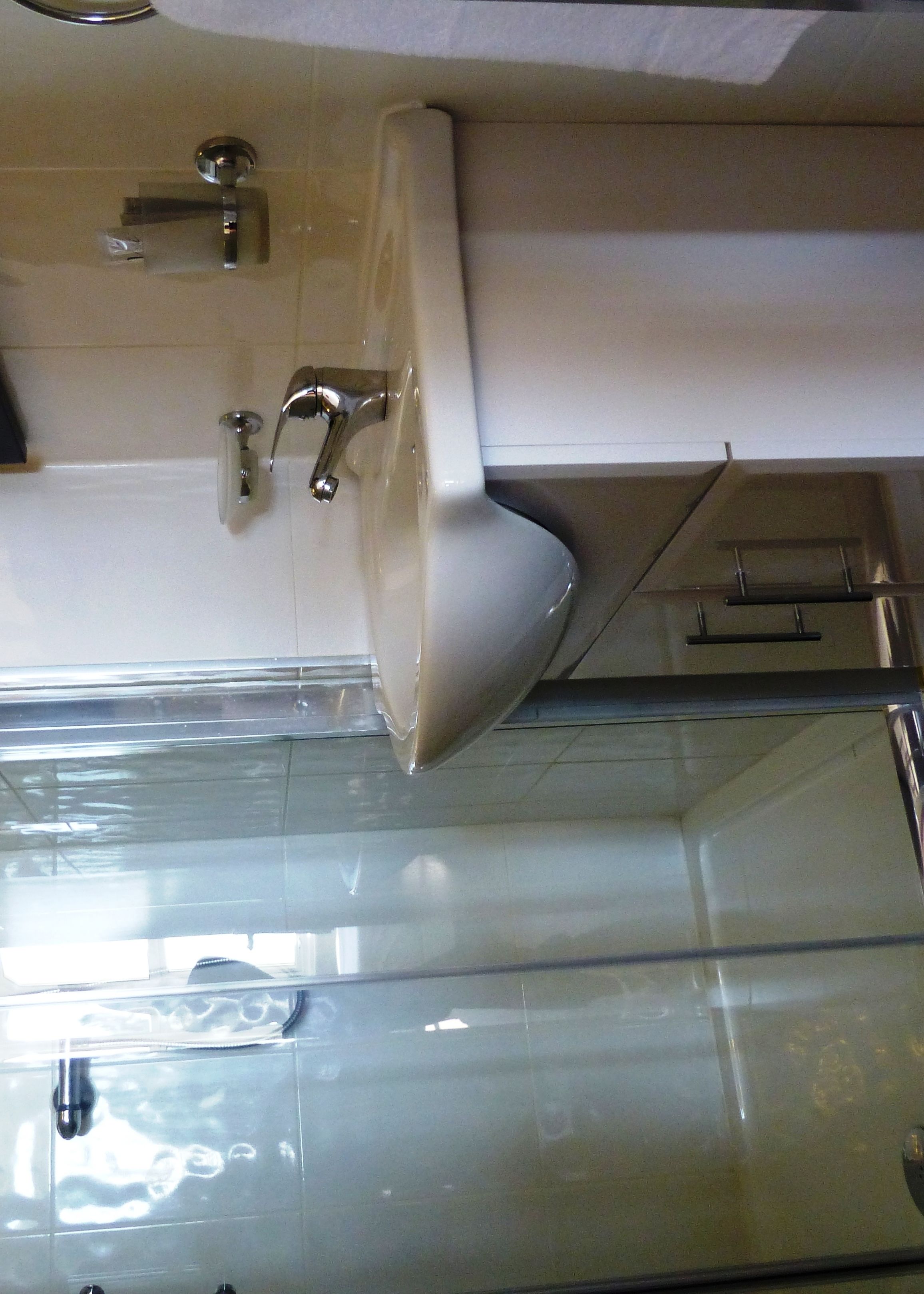 A bathroom with a white sink, a mirror, and a glass shower enclosure.